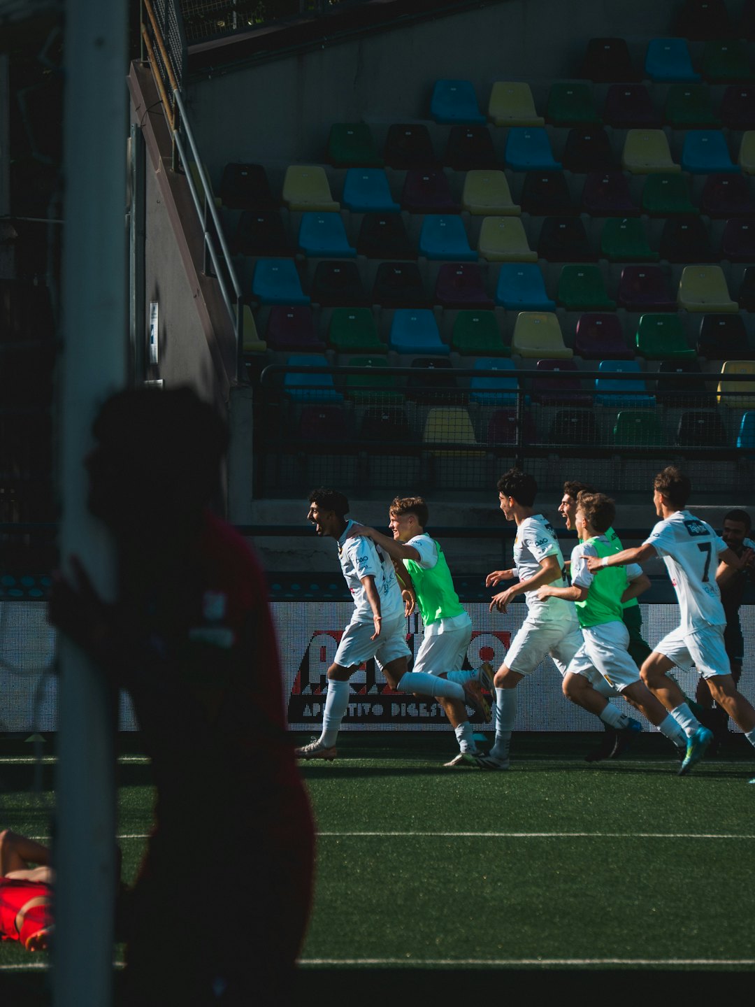 Soccer players in white and green jerseys celebrate on a field.