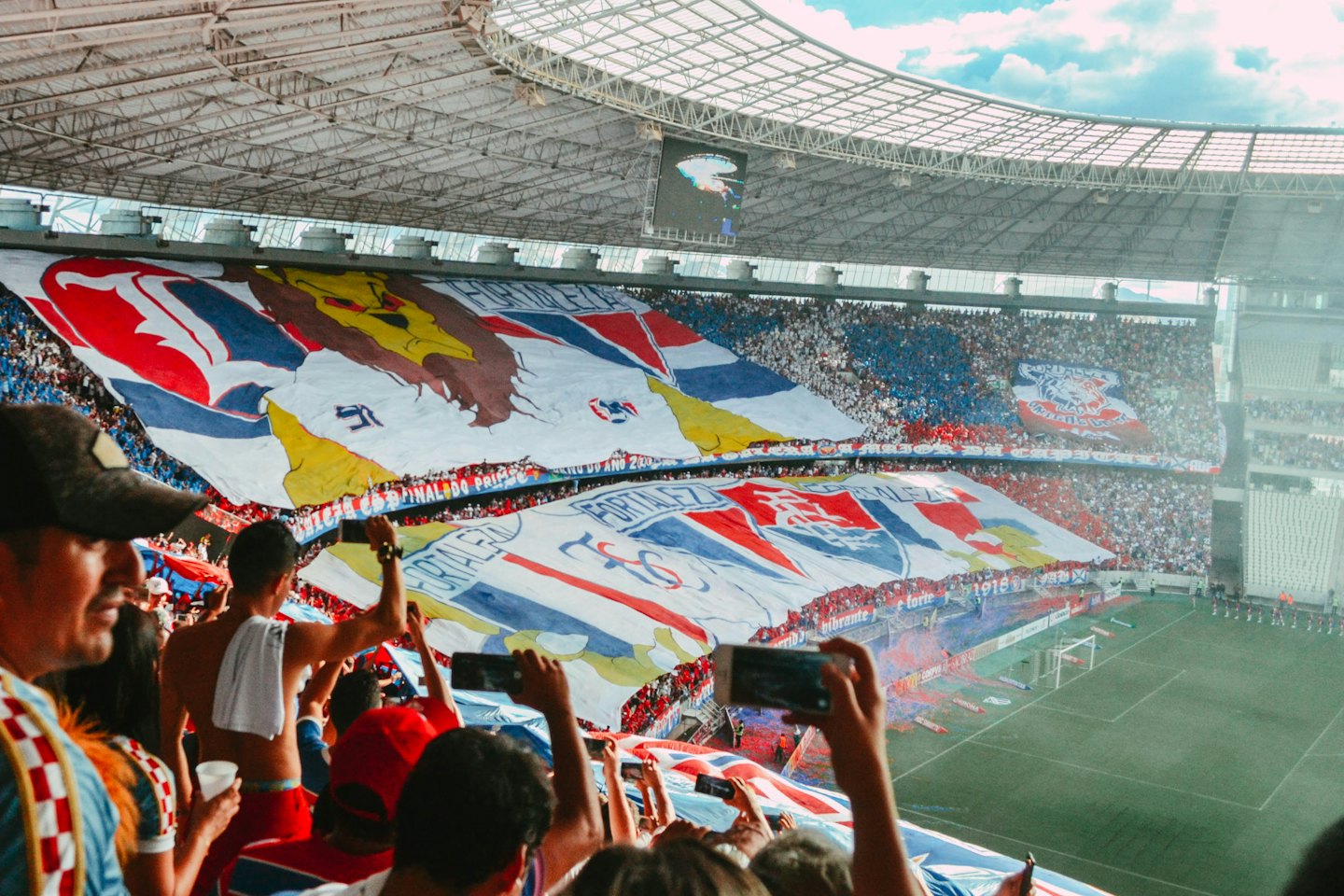 Spectators at a football stadium holding banners displaying Fortaleza.