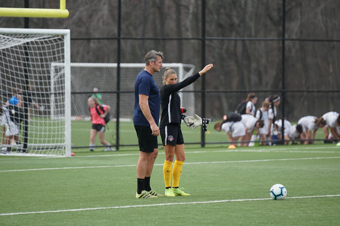 A soccer coach talks to a player on the field.