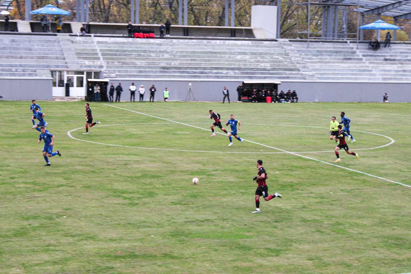 Players in blue and red uniforms compete on a field.