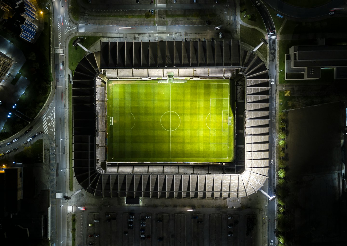 An illuminated football stadium at night with light trails from cars.
